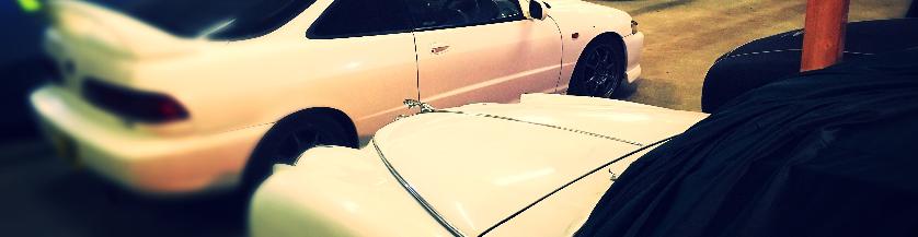 Two white cars. One is a classic and the other a popular sports car stored safely indoors.